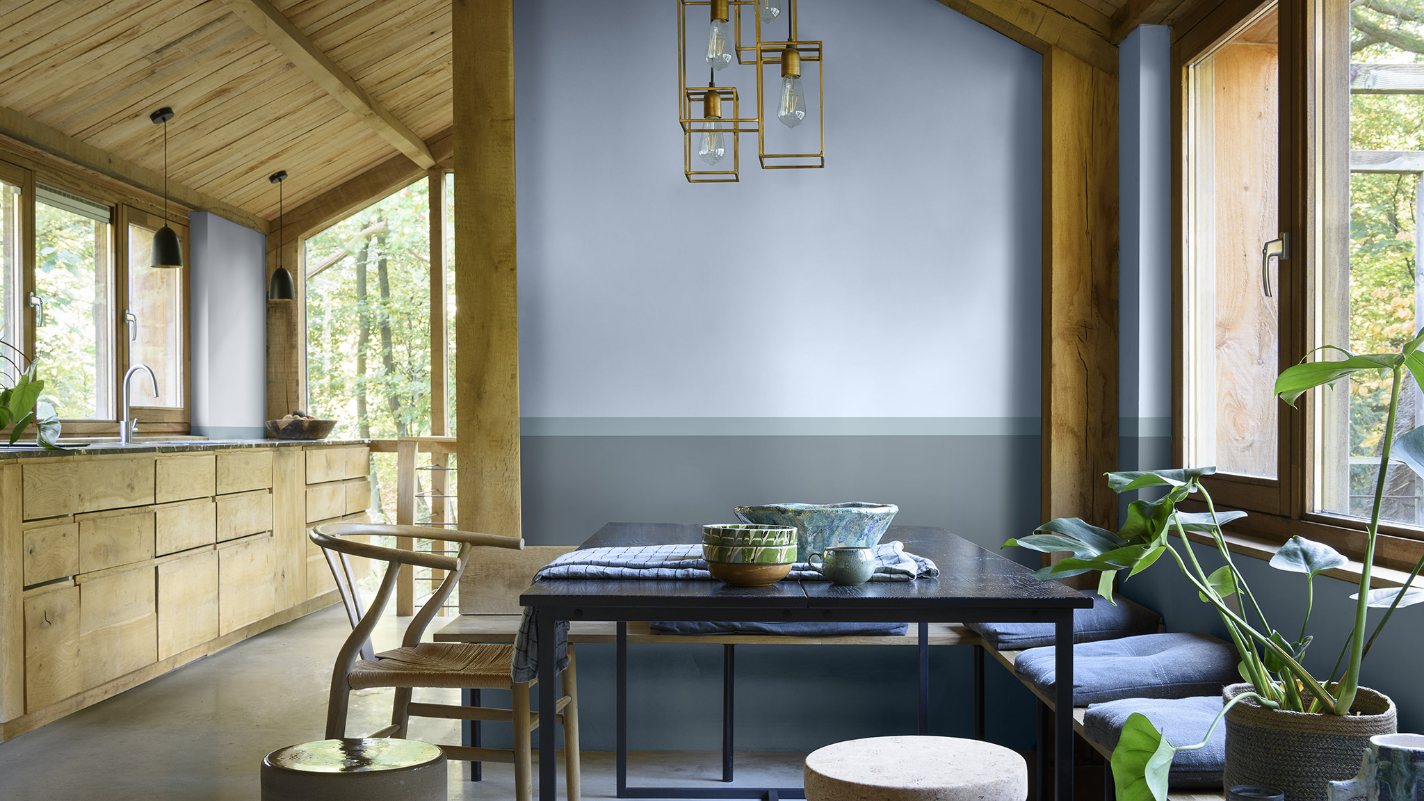 Sala de estar e cozinha integrada decorada com a cor Melodia Suave da Tintas Coral. Os tons de azuis e verdes combinados com móveis de madeira criam possibilidades de decoração inspiradas na natureza. 